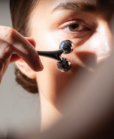 Woman Using Roller For At Home Facial Technique