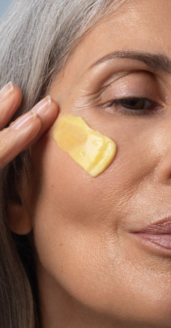 Woman Applying Face Cream To Cheek