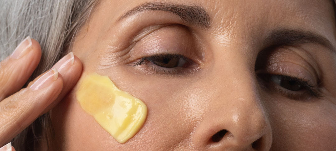 Woman Applying Face Cream To Cheek